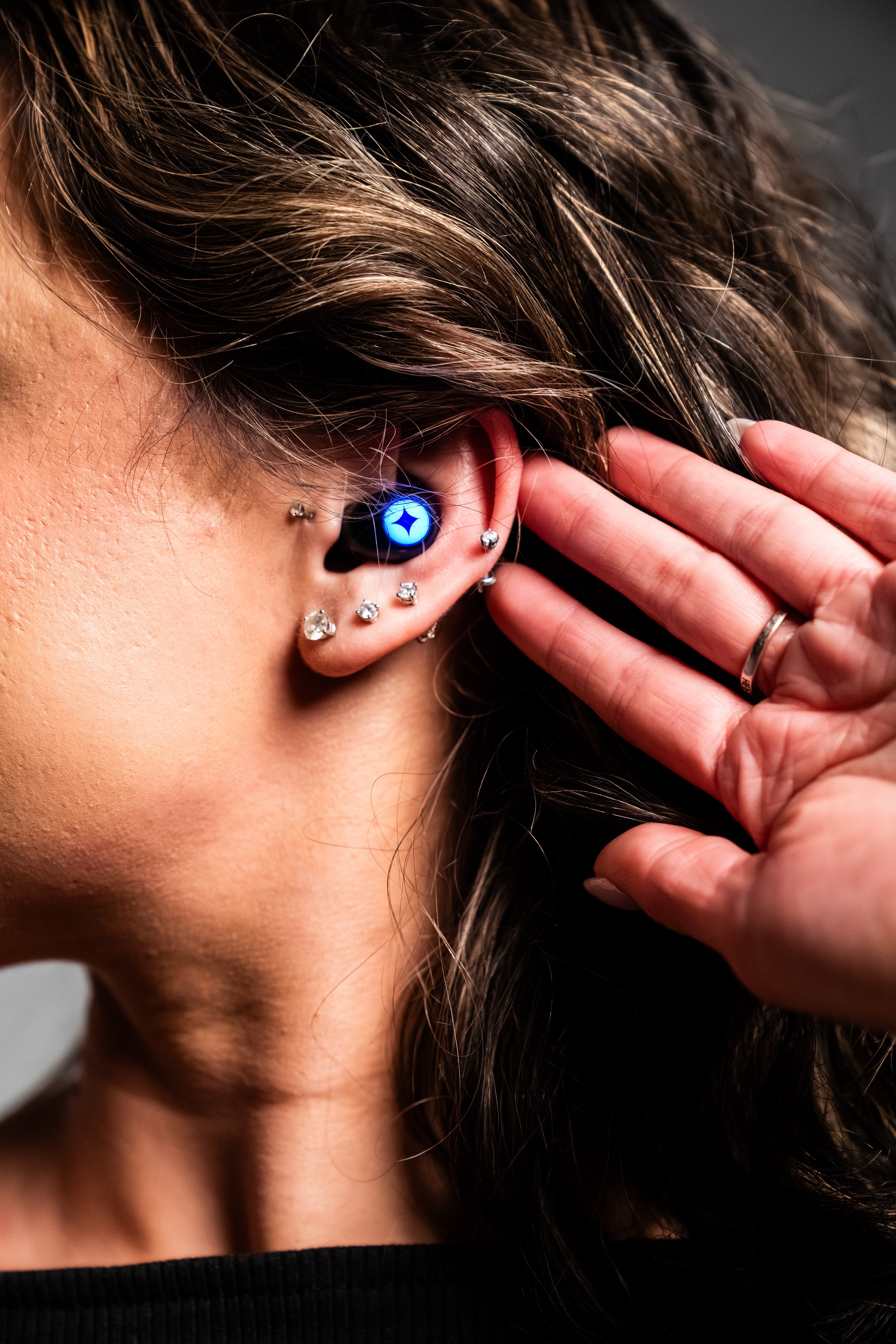 Person wearing a glowing LUMENEARZ Aura earplug